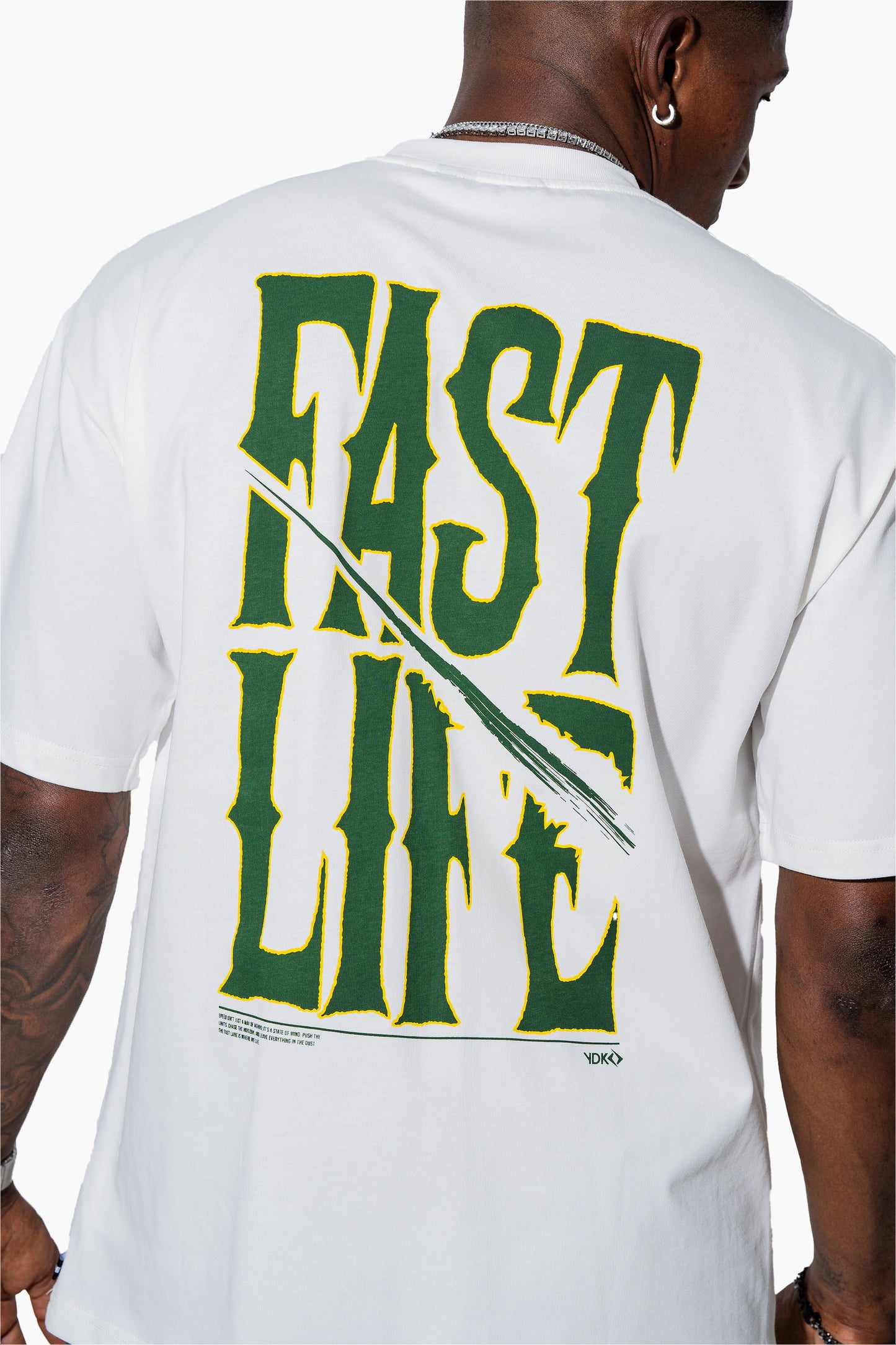 Man wearing an off-white t-shirt with FAST LIFE on it and green shorts on a white background