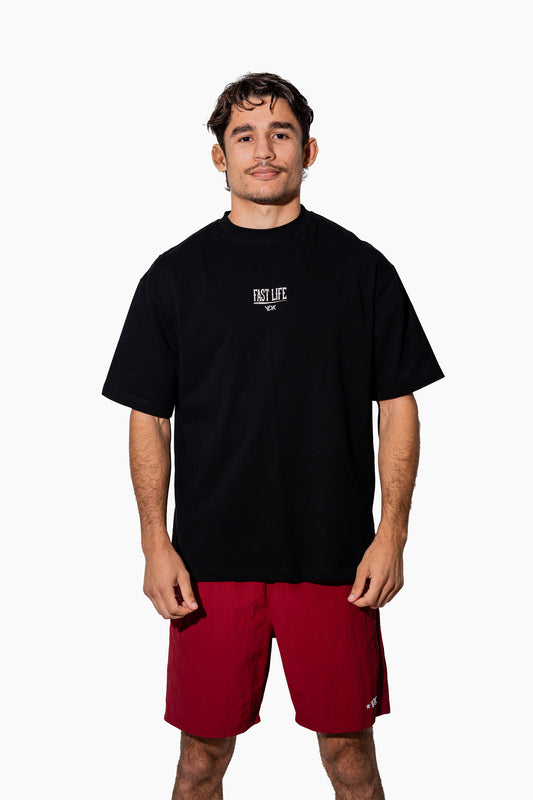 Man wearing a black t-shirt with FAST LIFE on it and red shorts on a white background