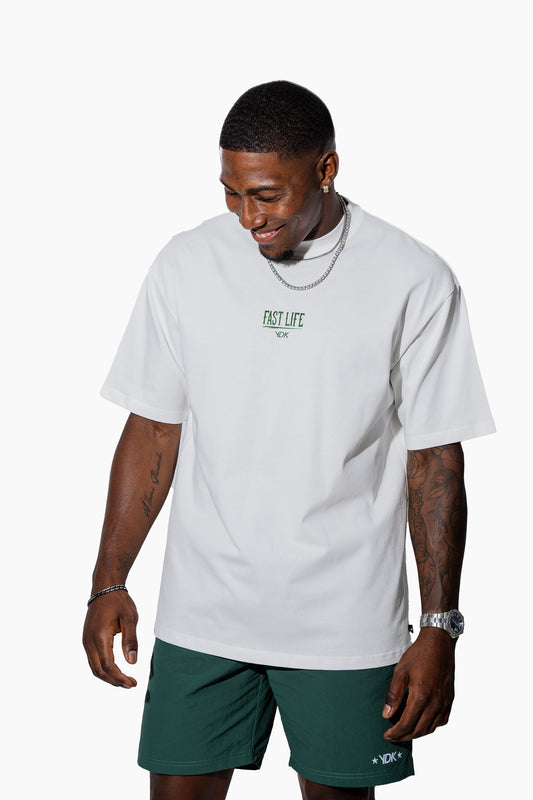 Man wearing an off-white t-shirt with FAST LIFE on it and green shorts on a white background