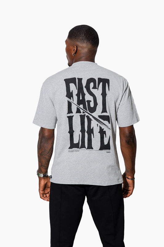 Man wearing a grey marl t-shirt with FAST LIFE on it and black pants on a white background