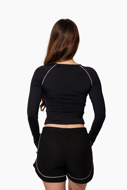 Woman wearing a black athletic outfit with red logos on a white background